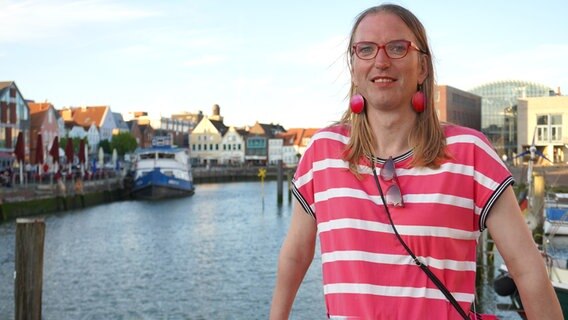 Transfrau Laura Schulze-Kölln steht im Hafen von Husum und lächelt in die Kamera. © NDR Foto: Elin Halvorsen