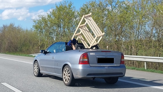 Ein Autofahrer transportiert ein großes Holzregal während der Fahrt in seinem Cabrio. © Presseportal Foto: Polizeidirektion Neumünster