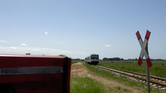 A tractor drives over an unrestricted level crossing just in front of a train.  © You Tube Channel 