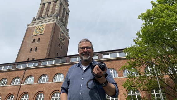 Bode Quante steht mit einer Kamera in der Hand vor dem Kieler Rathaus. © NDR Foto: Andrea Schmidt