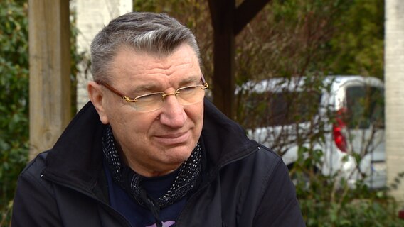 Ein Mann sitzt an einem Tisch und wird interviewt.  