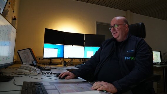 Andreas Dedeke sitzt lächelnd an einem Schreibtisch vor einem Bildschirm. © NDR Foto: Hauke Bülow