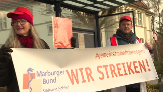 Protestierende des UKSH Lübeck mit einem Schild mit der Aufschrift "Wir streiken". Protestierende des UKSH Lübeck mit einem Schild mit der Aufschrift "Wir streiken". © NDR