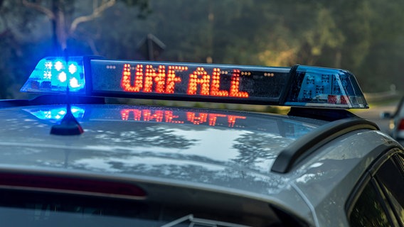 Ein Einsatzfahrzeug der Polizei steht mit eingeschaltetem Blaulicht an einem Unfallort an einer Landstraße. © IMAGO / Fotostand 