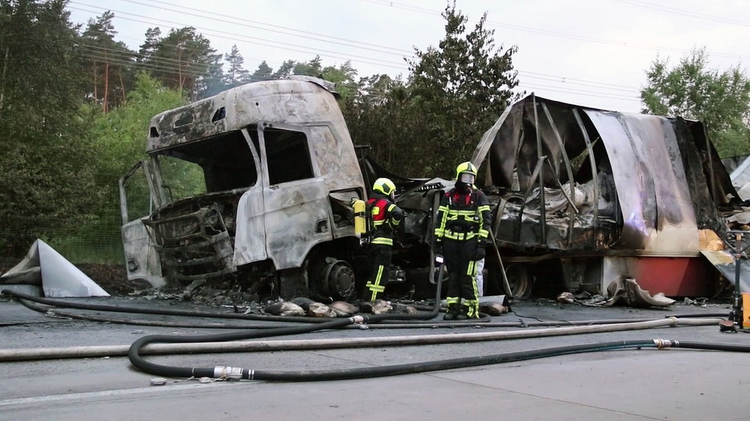 Zwei Feuerwehrleute stehen an einem ausgebrannten Lkw nach einem Unfall auf der A24.