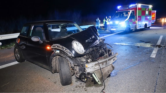Das schwarze Unfallauto steht quer auf der Fahrbahn, im Hintergrund ein Rettungswagen. © Florian Sprenger Foto: Florian Sprenger