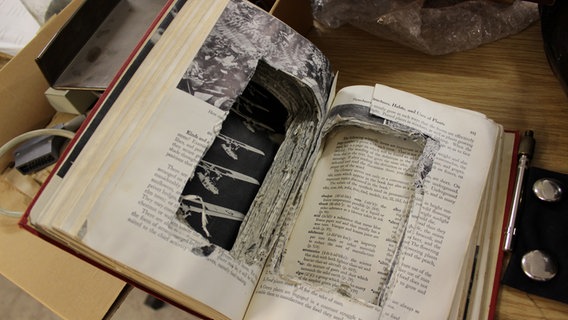 Ein aufgeklapptes Buch, in dem Seiten zu einem Versteck eingeschnitten wurden. © NDR Foto: Vera Vester
