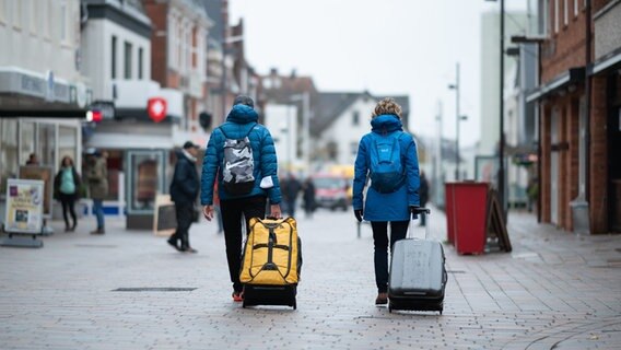 Urlauber gehen mit ihren Koffern durch die Fußgängerzone von Westerland auf Sylt. © dpa-Bildfunk Foto: Daniel Reihnardt, dpa