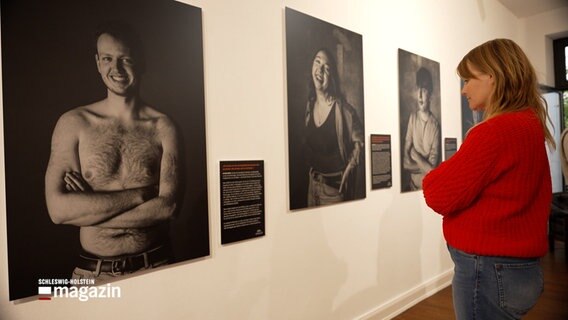 Eine Frau betrachtet eine Ausstellung über Menschen mit Narben. © NDR 