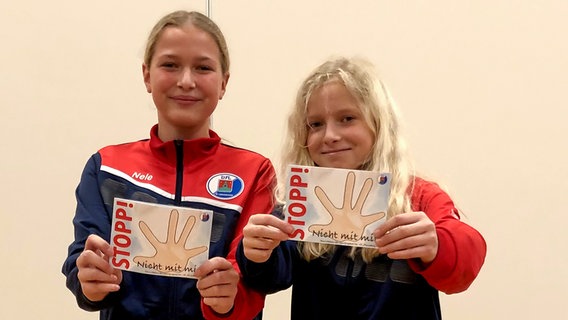 Zwei junge Sportlerinnen des Vfl Pinneberg präsentieren einen Comic. © NDR Foto: Finn Ole Martins