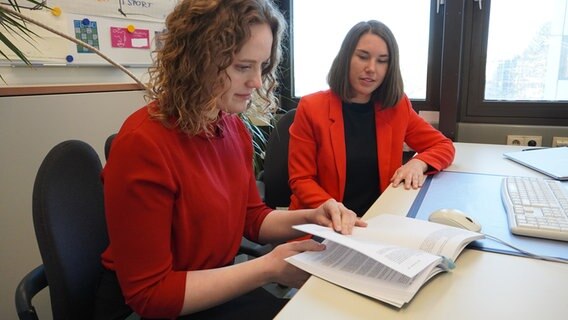 Zwei Personen sitzen an einem Schreibtisch und blättern in einem Buch. Zwei Personen sitzen an einem Schreibtisch und blättern in einem Buch. © NDR Foto: Elin Halvorsen