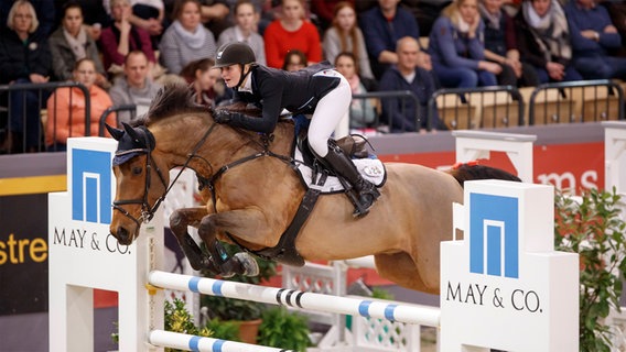 Janne Meyer-Zimmermann springt mit einem Pferd über ein Hindernis © reitturnier-neumuenster.de 