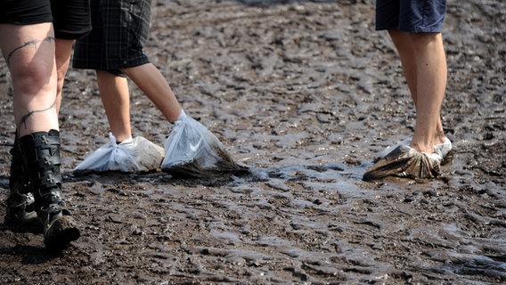 Besucher des Wacken-Festivals laufen mit Plastiktüten an den Füßen durch Matsch © dpa-Bildfunk Foto: Carsten Rehder