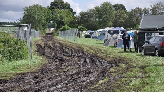 Entlang des Campingplatzes verläuft eine matschige Straße. © NDR Foto: Jörn Schaar