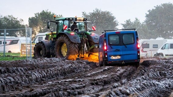 Gribbohm: Autos werden mithilfe eines Traktors auf das Gelände des Heavy-Metal-Festivals in Wacken durch den Schlamm gezogen. © Daniel Bockwoldt/dpa/Daniel Bockwoldt 