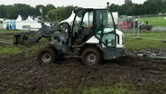 Eine Baumaschine hat sich auf dem schlammigen Gelände des Wacken Open Air festgefahren. © NDR Foto: NDR Screenshots