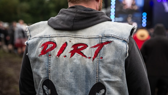 Auf der Rückseite einer Jeans-Weste steht in Großbuchstaben: D.I.R.T. © NDR Foto: Christoph Klipp