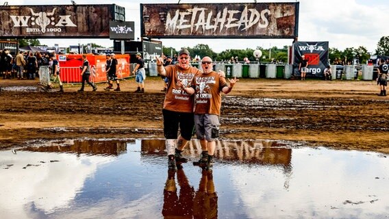 Wacken: Zwei Männer feiern beim Wacken Open Air an einer Schlammpfütze vor dem Veranstaltungsgelände. © dpa Bildfunk Foto: Axel Heimken