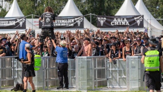Zehntausende Menschen warten hinter eine Absperrung zu einem Festivalgelände. © NDR Foto: Dominik Dührsen