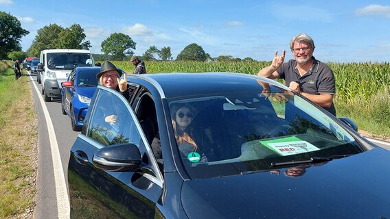 Eine Frau und ein Mann lehnen an ihrem Auto, während sie bei der Anreise zum Wacken-Festival im Stau stehen © NDR Foto: Laura Albus