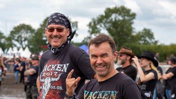 Zwei Männer lächeln im Wacken Dress in die Kamera © NDR Foto: Lena Storm