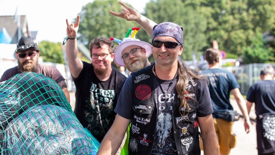 Wacken Besucher schieben ihr Gepäck vom Gelände und sind fröhlich dabei © NDR Foto: Lena Storm