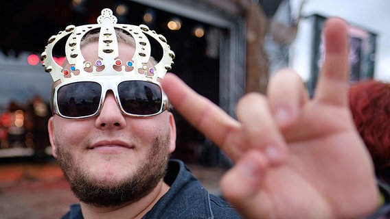 Ein Besucher des Wacken Open Air 2016 trägt eine Plastikkronen-Sonnenbrillen-Kombination. © dpa/bildfunk Foto: Axel Heimken