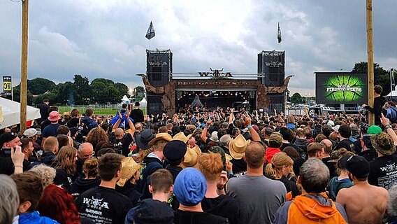 Heavy-Metal-Fans feiern 2016 das Orchester der freiwilligen Feuerwehr Wacken. © dpa/bildfunk Foto: Axel Heimken