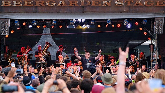 Heavy-Metal-Fans feiern 2016 das Orchester der freiwilligen Feuerwehr Wacken. © dpa/bildfunk Foto: Axel Heimken