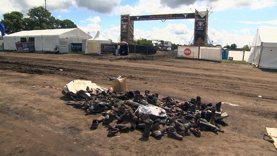 Mit Matsch verunreinigte Schuhe und andere Gegenständie liegen zusammengeräumt auf dem Gelände des Wacken Open Air Festivals © NDR 