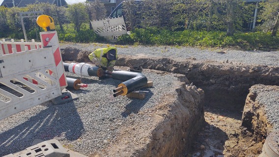 Ein Arbeiter schweißt an einem Nahwärmerohr neben einem ausgehobenen Schacht in Hürup. Ein Arbeiter schweißt an einem Nahwärmerohr neben einem ausgehobenen Schacht in Hürup. © NDR Foto: Peer-Axel Kroeske