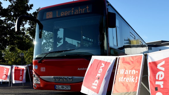 Ein Bus der Firma Autokraft steht hinter einem Schild mit der Aufschrift "Warnstreik". © picture alliance / dpa Foto: Carsten Rehder