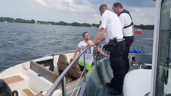 Zwei Mitarbeiter der Wasserschutzpolizei kontrollieren einen Mann auf einem Boot in der Kieler Förde. © Cassandra Arden Foto: Cassandra Arden