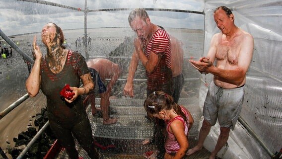 Teilnehmer der Wattolümpiade waschen sich den Schlamm vom Körper © dpa - Bildfunk Foto: Axel Heimken