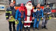 Mitglieder der Berufsfeuerwehr Kiel sind verkleidet als Weihnachtsmann und Superhelden. © Kai Peuckert 