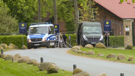 Ein Kleinbus der Polizei und ein anderer Kleinbus stehen vor einem Tor des Schlossgut Weissenhaus. © NDR 