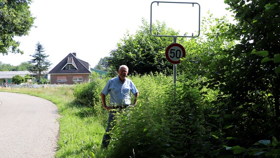 Manfred Schmidt steht vor einem leeren Ortsschild. © NDR Foto: Tobias Senff