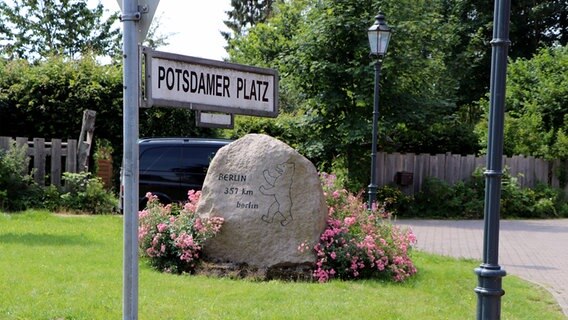 Das Straßenschild für den "Potsdamer Platz" in Berlin im Kreis Segeberg steht vor einem Stein, der auf die Partnerschaft zum großen Berlin hinweist. © NDR Foto: Tobias Senff