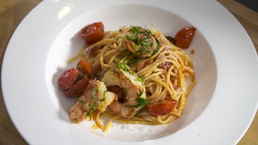 Spaghetti with shrimps and cherry tomatoes are laid out on a plate.  © NDR 