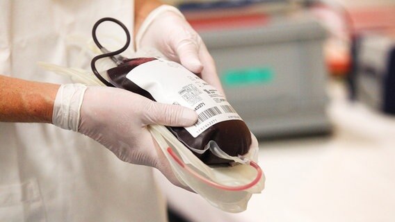 Eine Person mit Einweghandschuhen hält eine gefüllte Blutkonserve in den Händen. © imago images Foto: Eibner