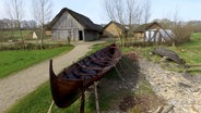 Ein Boot steht vor Häusern des Wikinger-Museums Haithabu. © picture alliance/dpa Foto: Carsten Rehder