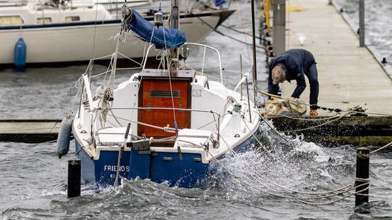 Ein Mann sichert ein Segelboot an einem Anlegesteg an der Kieler Förde gegen eine erwartete Sturmflut. © dpa-Bildfunk Foto: Axel Heimken