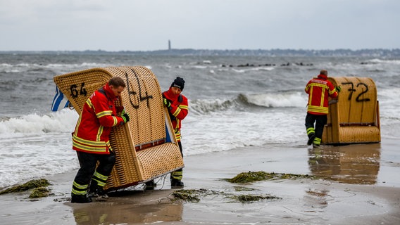 Einsatzkräfte der Feuerwehr versuchen in Kiel-Schiksee einen Strandkorb vor den Flutwellen der Ostsee zu sichern. © dpa-Bildfunk Foto: Axel Heimken