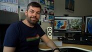 Wetterexperte Sebastian Wache sitzt in einem Büro und macht die Wettervorhersage. © NDR 