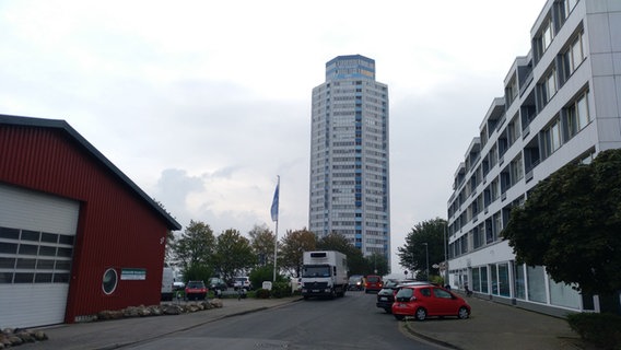 Die Zufahrtsstraße zum Wikingturm: links die Bootshalle, dahinter ein Parkplatz und das Hochhaus, rechts ein moderner Häuserblock.  Foto: Peer-Axel Kroeske
