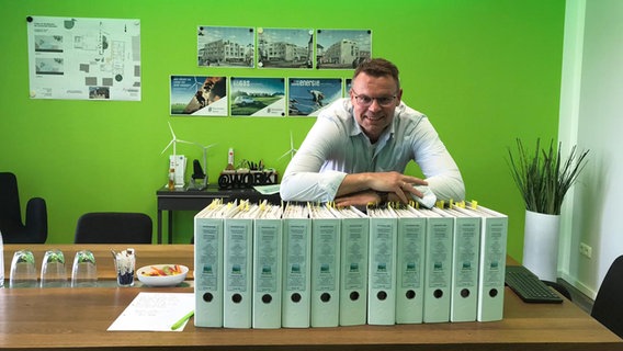Matthias Frauen lehnt über dem Antrag für eine Windkraftanlage. Er ist Geschäftsführer der WindPlan Witthohn + Frauen GmbH & Co. KG, einem Projektentwickler für erneuerbare Energie Matthias Frauen lehnt über dem Antrag für eine Windkraftanlage. Er ist Geschäftsführer der WindPlan Witthohn + Frauen GmbH & Co. KG, einem Projektentwickler für erneuerbare Energie © Matthias Frauen