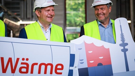 Robert Habeck (Grüne, rechts) und Jens Kerstan (Grüne) halten Schilder mit dem Text «Wärme» bei einem Pressetermin zur Fertigstellung einer Wind-zu-Wärme-Anlage (Power-to-Heat-Anlage) auf dem Gelände des Heizkraftwerks Wedel. © dpa-Bildfunk Foto: Christian Charisius