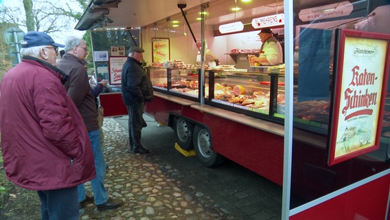 Kunden stehen vor einem Fleischstand auf einem Wochenmarkt in Westensee. © NDR 