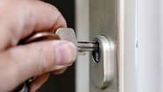 Eine Person schließt eine Wohnungstür mit einem Schlüssel auf. © picture alliance/dpa Foto: Markus Scholz