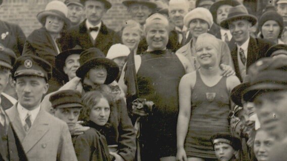 Ein Gruppe von Menschen posieren auf einem alten schwarzweiß Foto.  